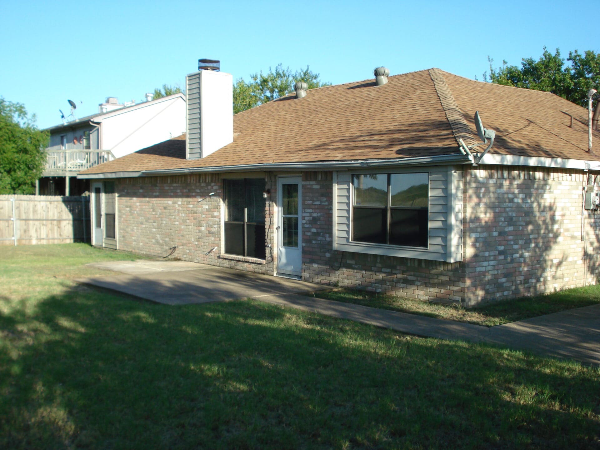 Single-story house with brown roof and stone exterior under clear sky.