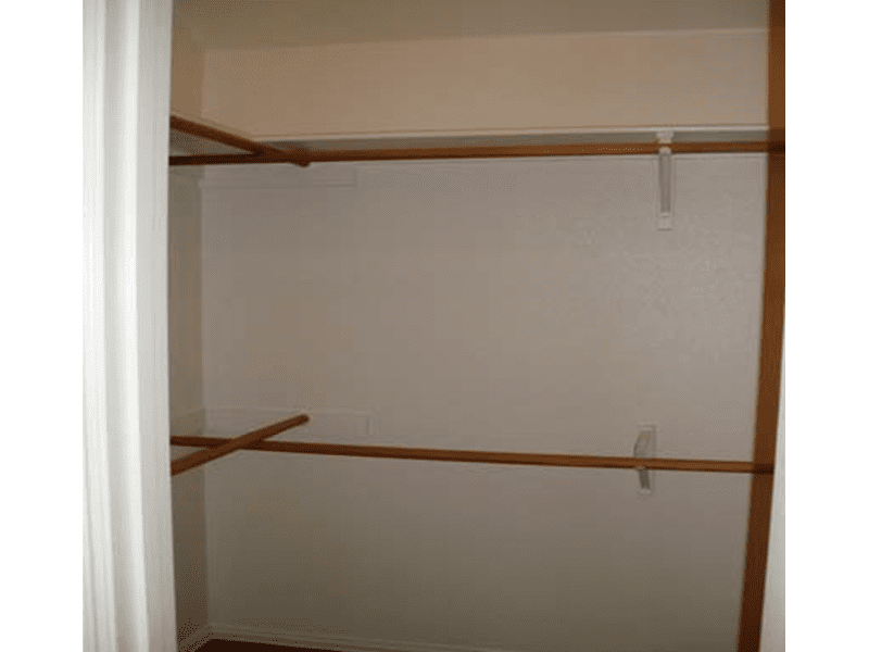 Empty closet with wooden rods and beige walls.