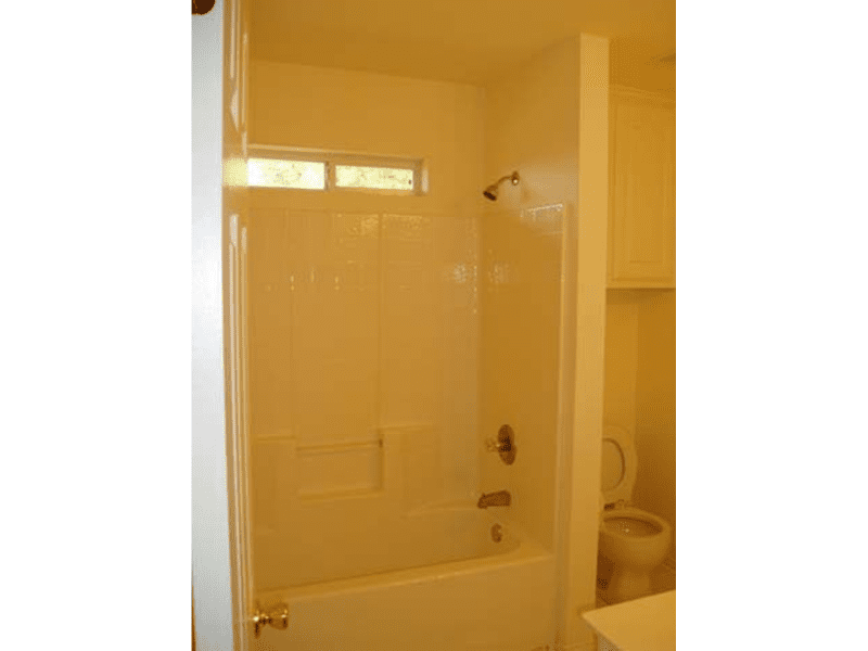 Bathroom with yellow walls and a white bathtub.