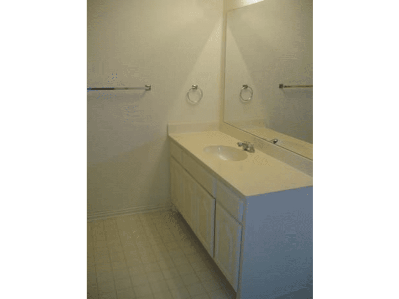 Minimalist bathroom with a large mirror and white vanity.