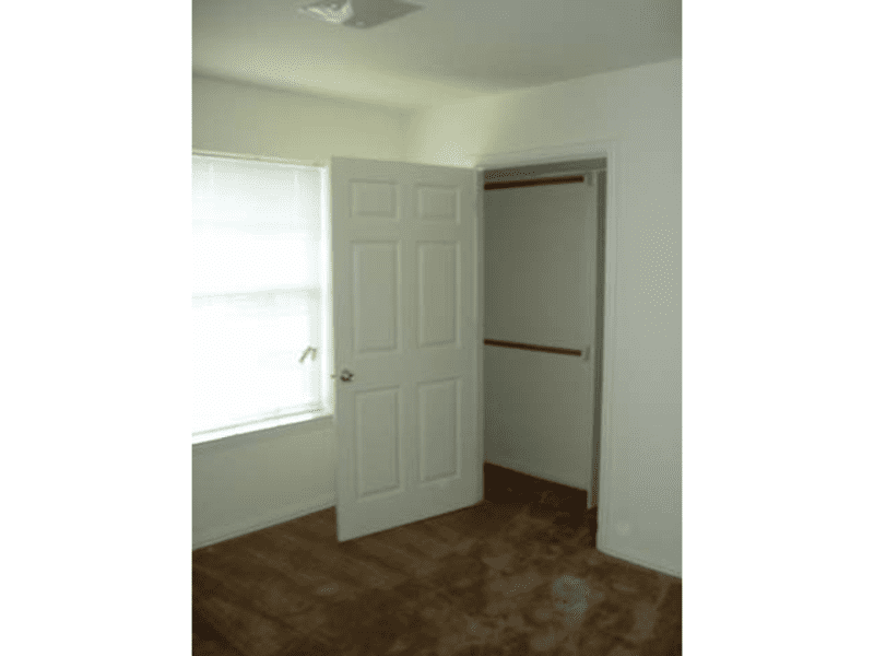 Empty room with an open closet door and window light.