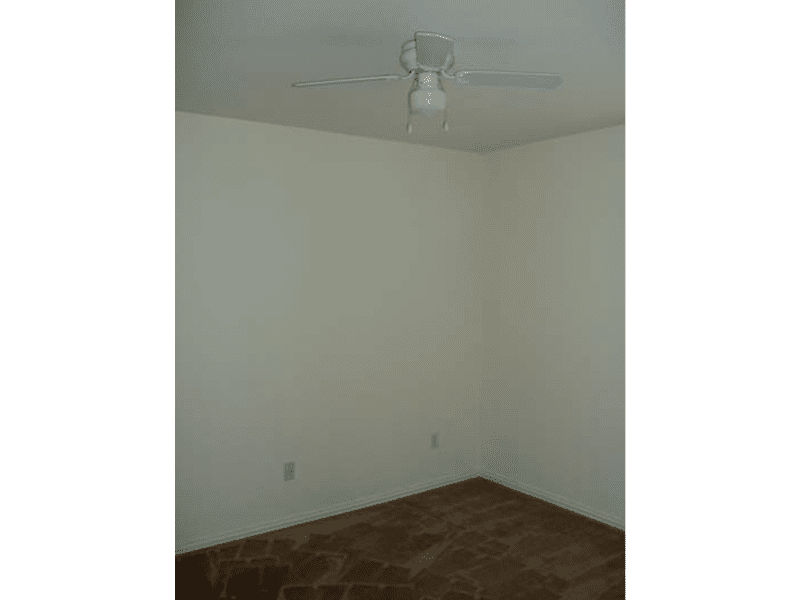 Empty room corner with beige walls and brown carpet.