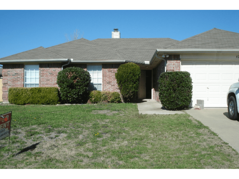 Suburban house with a neatly trimmed lawn and shrubbery.