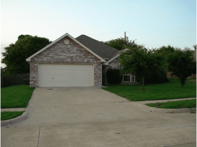 A suburban brick house with a two-car garage and a concrete driveway.