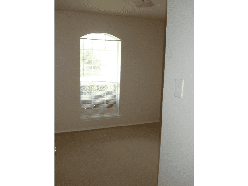 Empty room with window covered by a sheer curtain.