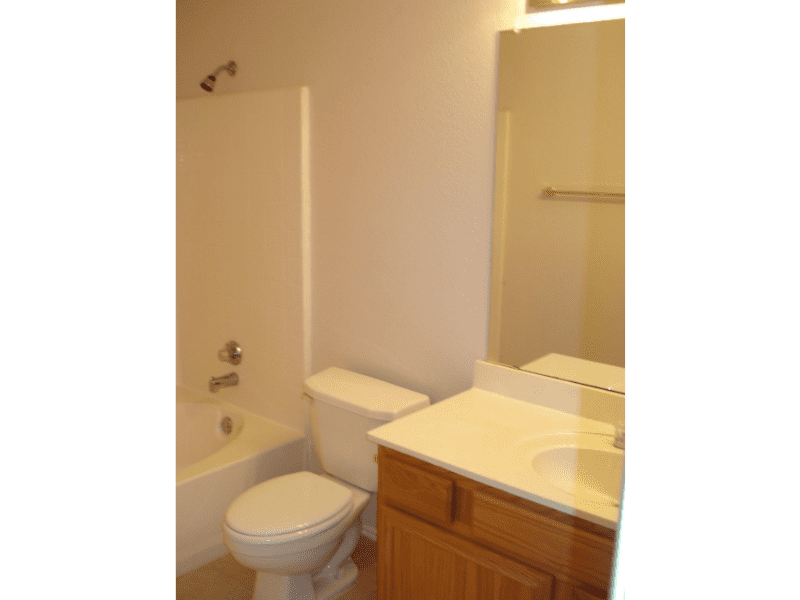 Small bathroom with bathtub, toilet, and wooden vanity.