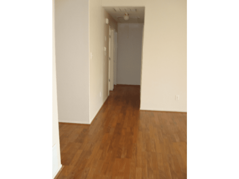 Empty room with wooden flooring and plain white walls.