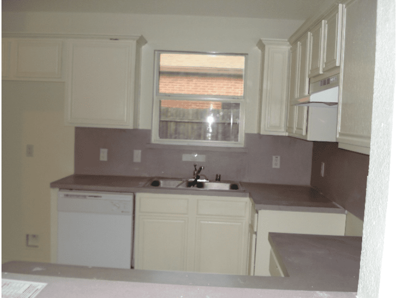 Empty kitchen with beige cabinets and a dishwasher.