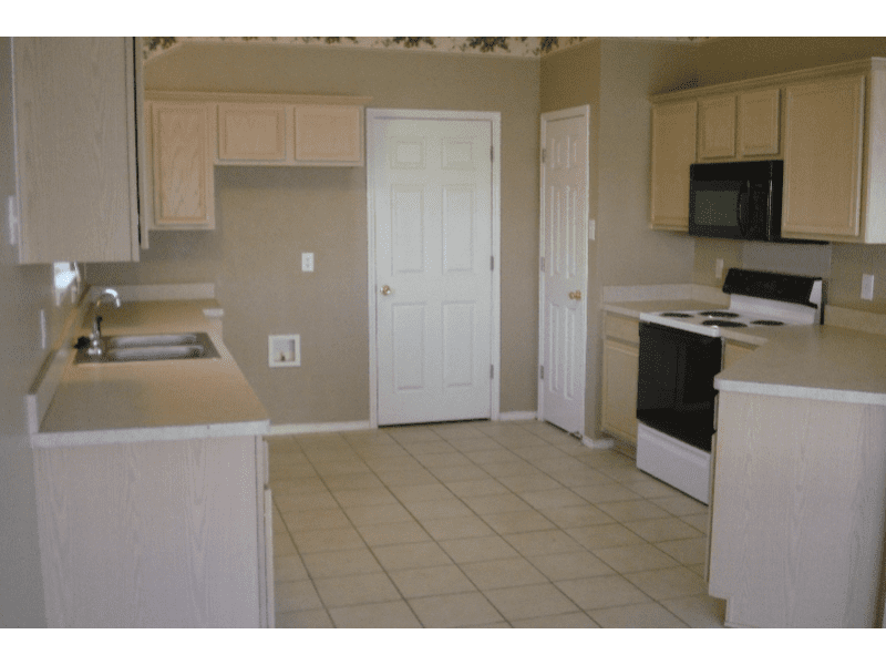 Empty kitchen with beige cabinets and tiled floor.