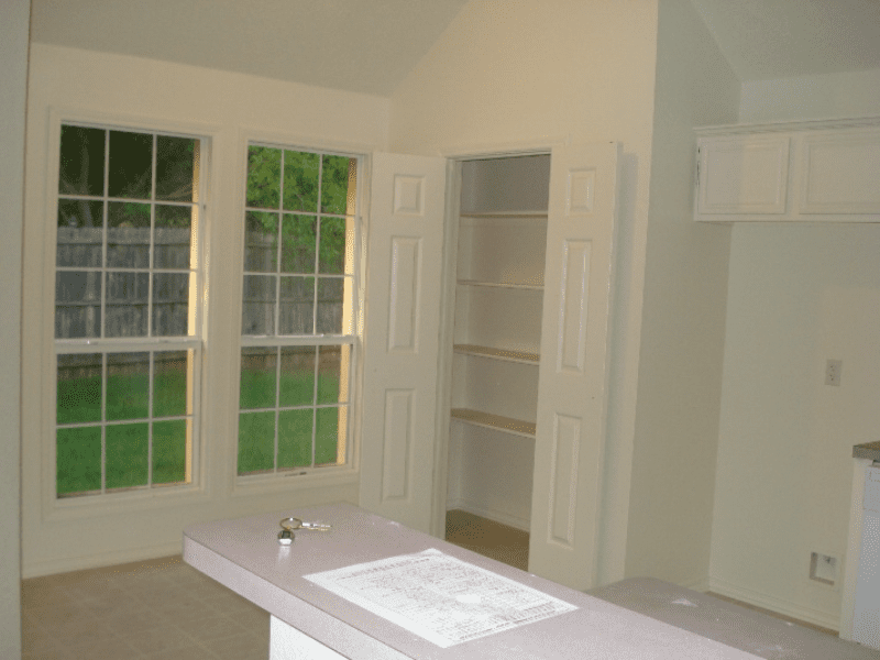 Empty room with large windows and built-in shelves.