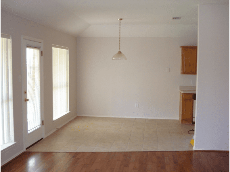 Empty dining area with carpet and pendant light near kitchen.