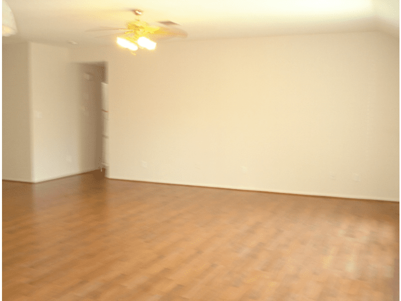 Empty room with wooden floor and ceiling fan.