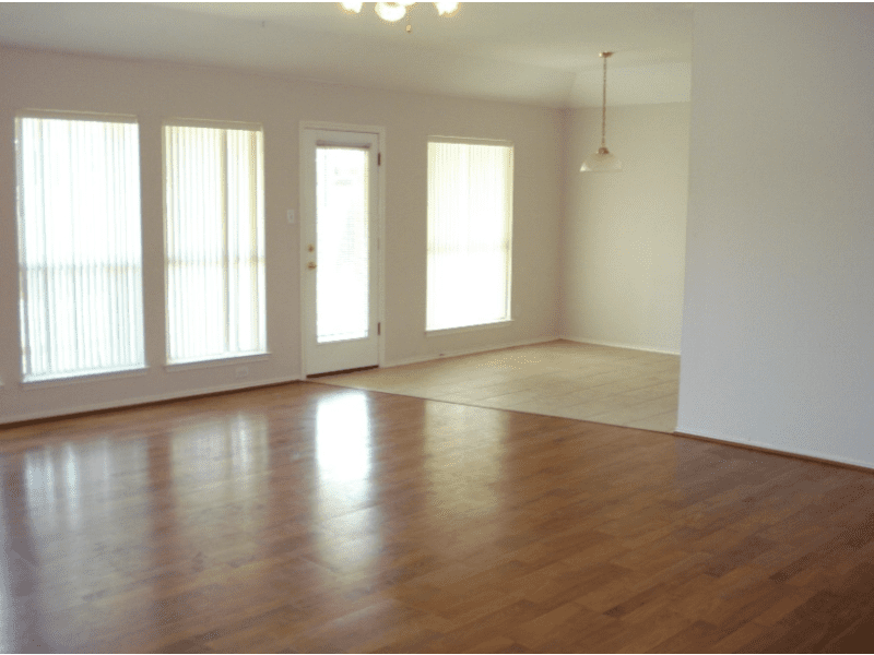 Empty room with large windows and wooden floor.