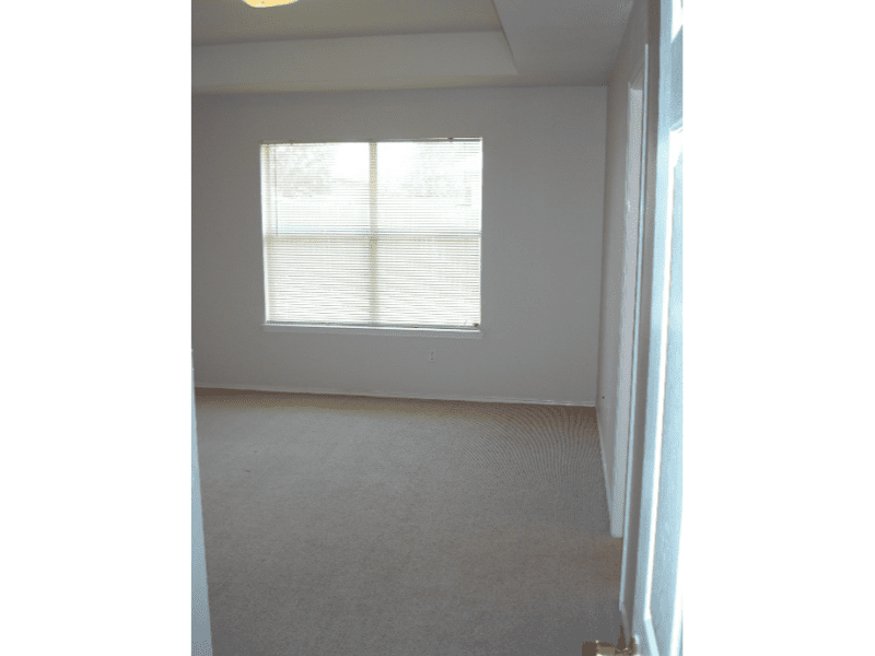 Empty room with carpet and window covered by blinds.