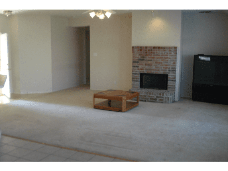 Spacious living room with beige carpet and brick fireplace.