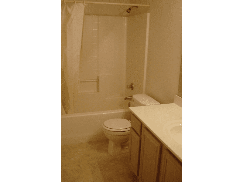 Clean bathroom with bathtub, toilet, and vanity.